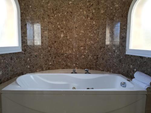 a white bath tub in a bathroom with two windows at Adel Locdenia in Els Poblets