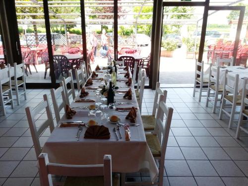 a long dining room with white tables and white chairs at Dogana Vecchia - Hotel & Residence B&B Ristorante & Pizzeria in Trivignano Udinese