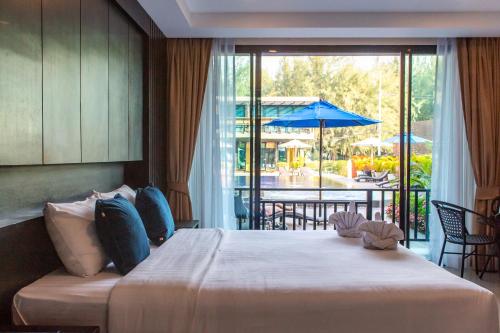 ein Schlafzimmer mit einem Bett und einem Balkon mit einem Sonnenschirm in der Unterkunft Sun Marina Cha-Am in Cha-am