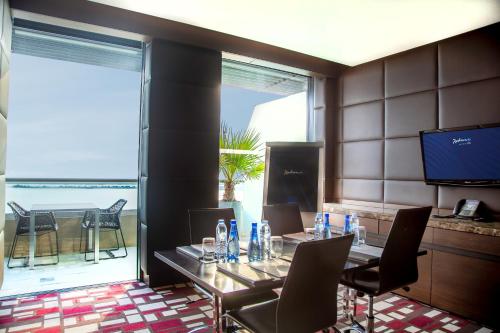 a dining room with a table and chairs and a television at Radisson Blu Hotel, Abu Dhabi Yas Island in Abu Dhabi