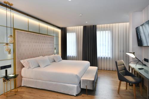 a bedroom with a large white bed and a desk at Barceló Ourense in Ourense
