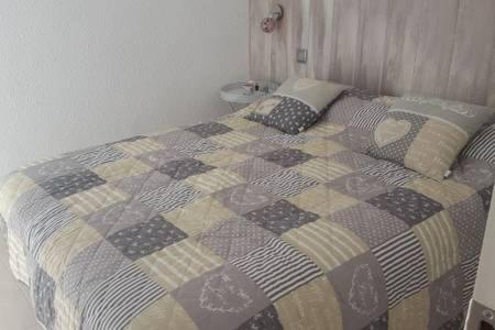 ein Bett mit einer Decke in einem Schlafzimmer in der Unterkunft COQUETO APARTAMENTO EN PLAYA DE ARO in Platja  d'Aro