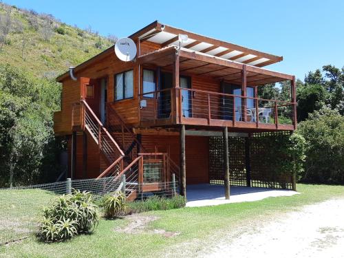 a wooden house with a balcony and a porch at "The Gatehouse", Goosebumps - Cottage in Lake Brenton on Knysna Lagoon in Brenton-on-Sea