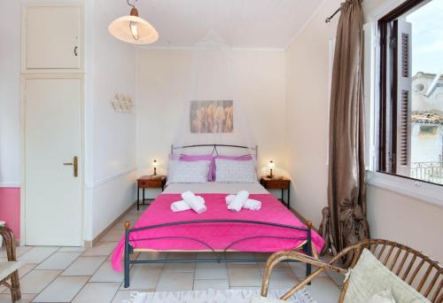 a bedroom with a pink bed with two towels at Mermaid cottage in Longos