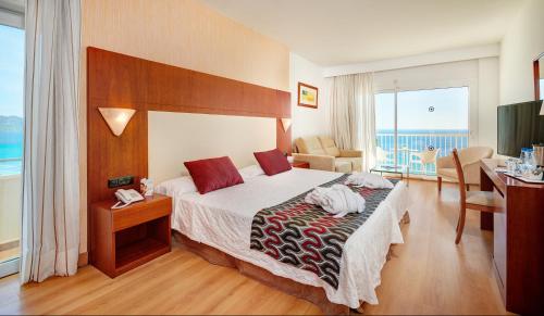 Pokój hotelowy z łóżkiem, biurkiem i pokojem w obiekcie CM Castell de Mar w Cala Millor