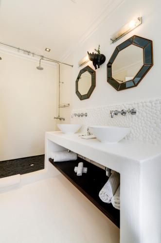 a bathroom with two sinks and two mirrors at The Post House Hotel - no children under the age of 16yrs in Greyton