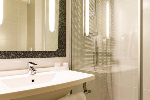 a white bathroom with a sink and a shower at Hotel ibis Evora in Évora