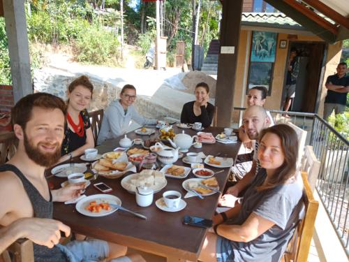 een groep mensen die rond een tafel zitten en eten bij Ella Mount Relax Cottage in Ella