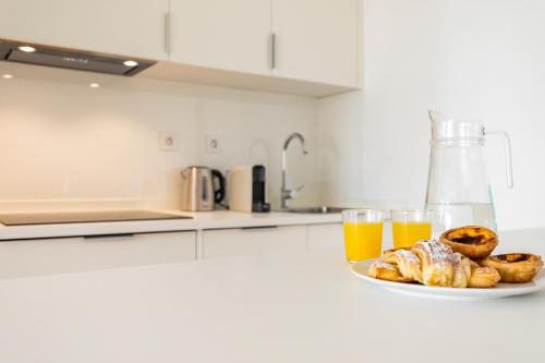 a plate of food and two glasses of orange juice at Belem Design Apartments by Homing in Lisbon