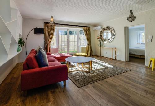 a living room with a red couch and a table at The Post House Hotel - no children under the age of 16yrs in Greyton