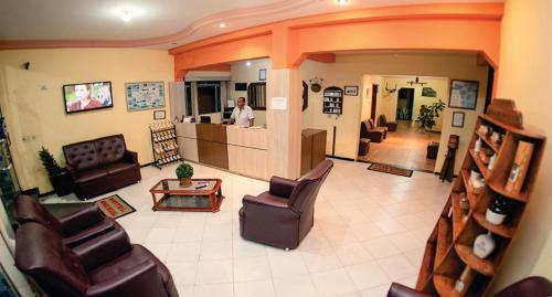 a man in a living room with chairs and tables at Hotel Minas Brasil in Salinas