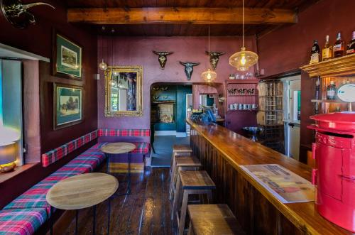 a bar with purple walls and wooden tables and benches at The Post House Hotel - no children under the age of 16yrs in Greyton