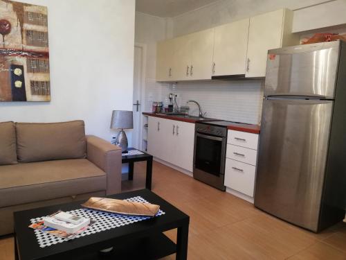 a small kitchen with a couch and a refrigerator at Efi Apartment in Paralio Astros