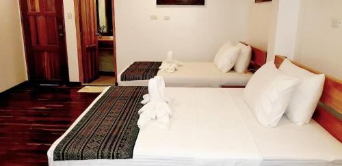 two beds in a room with white sheets and pillows at DiveGurus Boracay Beach Resort in Boracay