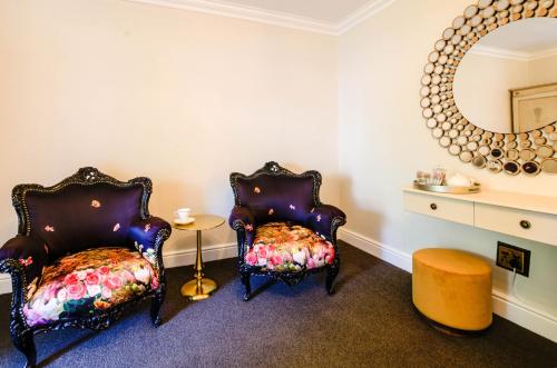 twee stoelen in een kamer met een spiegel bij The Post House Hotel - no children under the age of 16yrs in Greyton