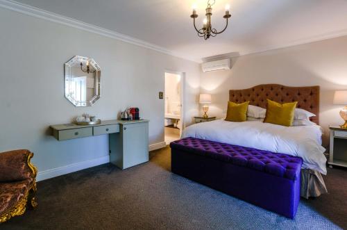 a bedroom with a purple bed and a mirror at The Post House Hotel - no children under the age of 16yrs in Greyton