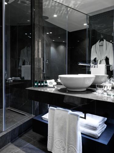 a bathroom with a sink and a shower with towels at Sofitel Athens Airport in Athens