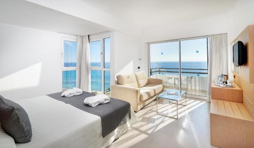 a bedroom with a bed and a couch and a chair at CM Playa del Moro in Cala Millor