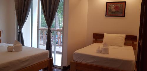two beds in a room with a window at DiveGurus Boracay Beach Resort in Boracay