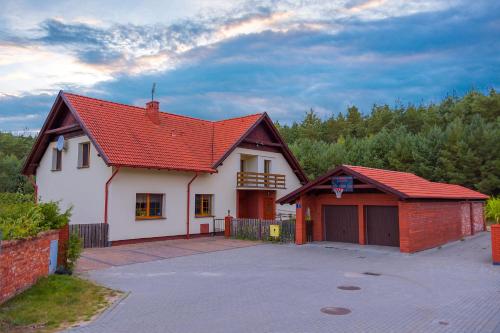 a white house with a red roof and a garage at Noclegi Przylesie in Rychnowy