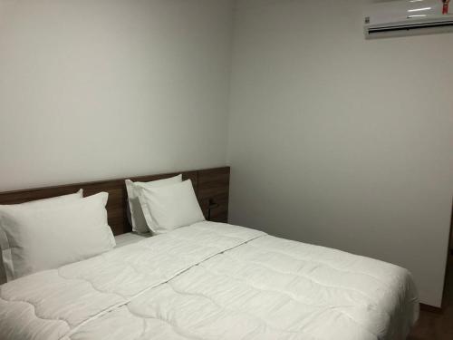 a bed with white sheets and pillows in a room at Hotel Matrix in Apucarana