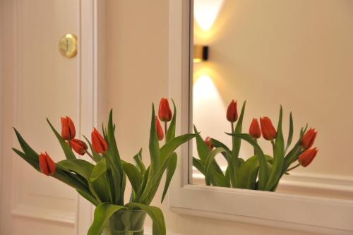 a vase of red tulips in front of a mirror at Hotel Miramar in Hamburg