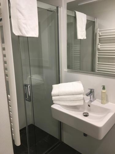a bathroom with a sink and a shower with towels at Ferienwohnungen & Monteurunterkunft "Mainbogen-Blick" in Untereuerheim