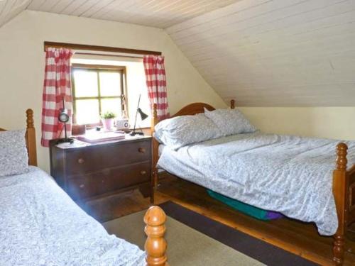 a bedroom with two beds and a desk and a window at Clooncorraun Cottage in Ballinrobe