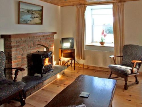 a living room with a fireplace and a tv at 1 Clancy Cottages in Kilkieran
