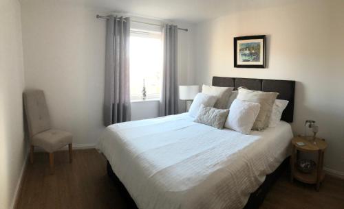a bedroom with a large white bed with a window at Hansen House Cardiff Apartment with Parking in Cardiff
