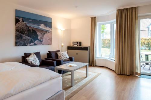a hotel room with a bed and a couch and a table at Ringhotel Hohe Wacht in Hohwacht
