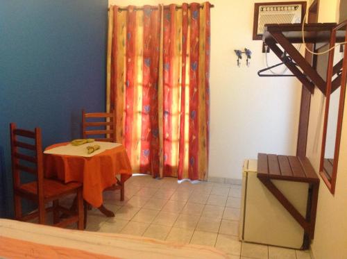 a dining room with a table and chairs and a curtain at Pousada Telhado Azul in Abraão