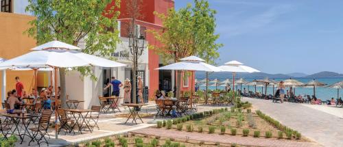 a patio with tables and chairs and umbrellas next to the water at Amadria Park Ivan in Šibenik
