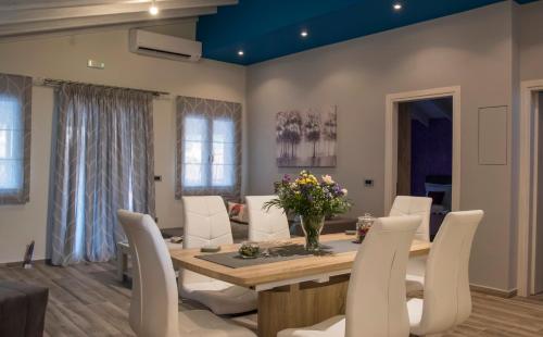 a dining room with a table and white chairs at Leonidas House in Parga