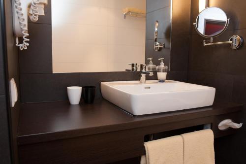 a bathroom with a white sink and a mirror at Stay2Munich Hotel & Serviced Apartments in Brunnthal