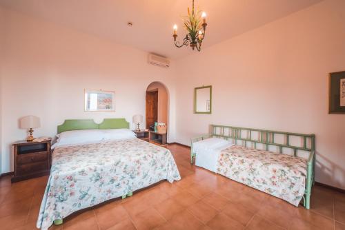 a bedroom with two beds and a table and a chandelier at Hotel Villa Sirina in Taormina