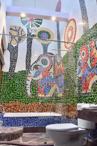 a bathroom with a mosaic wall with a toilet at Rock Villa by Baaya in Mussoorie