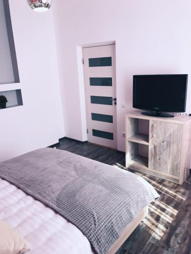 a bedroom with a bed and a flat screen tv at Apartment Ternopil Світло не вимикають in Ternopilʼ