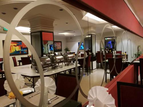 a restaurant with tables and chairs and a mirror at Smart Hotel in Lahore