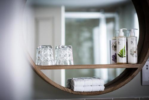 a mirror with towels and glasses on a shelf at The Fox in Winchester