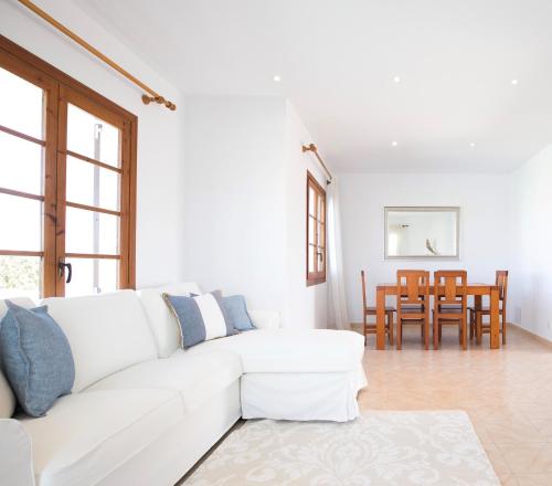 a white living room with a white couch and a table at Villa Margarita in Es Mercadal