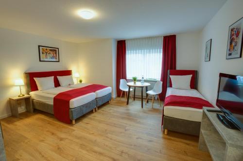 a hotel room with two beds and a table at Hotel Leo Mühlhausen in Mühlhausen
