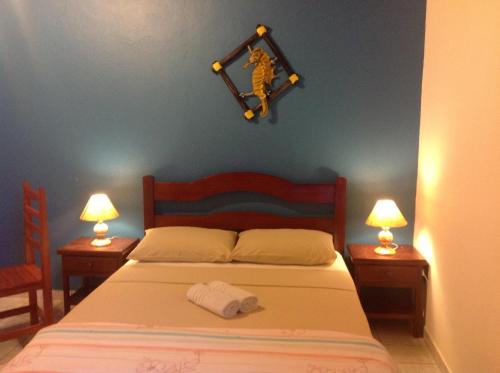 a bedroom with a bed with two nightstands and two lamps at Pousada Telhado Azul in Abraão