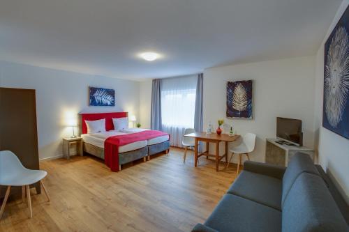 a bedroom with a bed and a couch and a table at Hotel Leo Mühlhausen in Mühlhausen