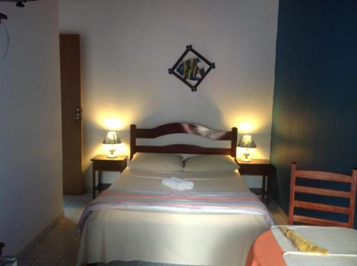 a bedroom with a bed with two tables and two lamps at Pousada Telhado Azul in Abraão