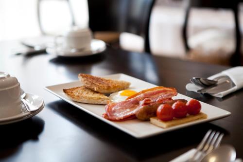een bord met ontbijtproducten op een tafel bij Tara Lodge in Belfast