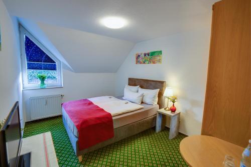 a small bedroom with a bed and a window at Hotel Leo Mühlhausen in Mühlhausen