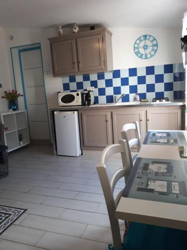 - une cuisine avec du carrelage bleu et blanc sur le mur dans l'établissement Chevrefeuille et Eglantine, à LʼÎle-dʼOlonne