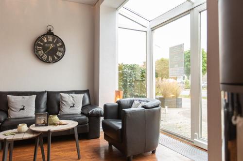a living room with a couch and a clock on the wall at Hotel Bavaria Oldenburg in Oldenburg
