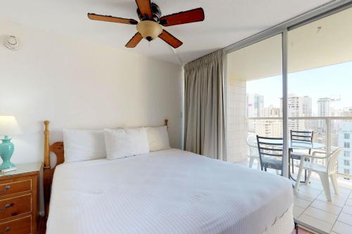 een slaapkamer met een bed en een plafondventilator bij Island Colony Suites in Honolulu
